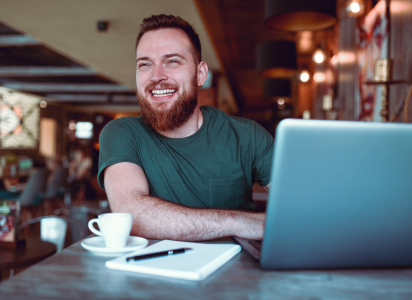 man in a happy mood because he's drinking coffee and working on laptop